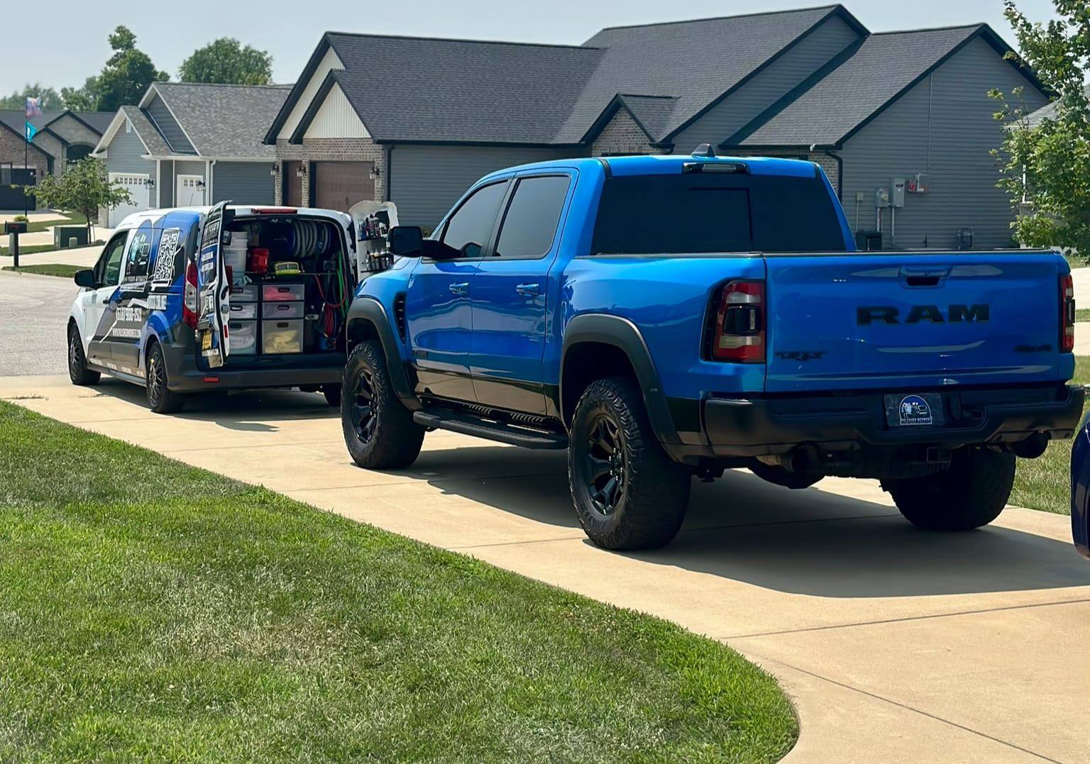 Glossy blue Ram TRX freshly detailed in a driveway with the Polished Midwest mobile detailing van behind it